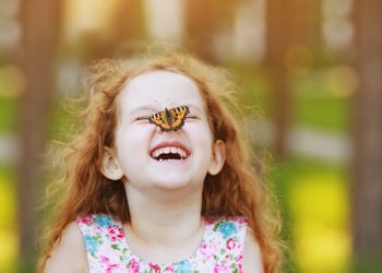 Funny laughing curly girl with a butterfly on his nose. Healthy smile with white teeth. Free breathing concept.