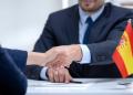 Spanish boss signing employment contract with immigrant employee, shaking hand